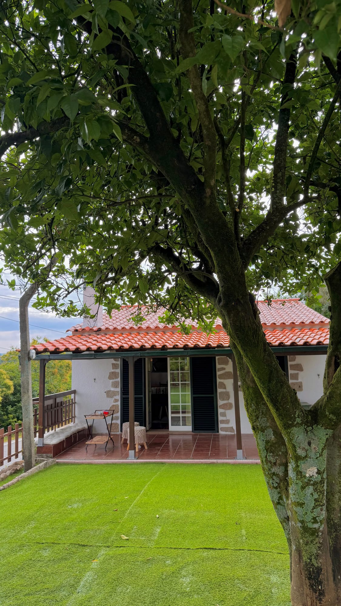 A casa de pedra rodeada pelo jardim e pelas árvores